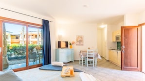 A bedroom with a bed, a desk, a chair, a table, and a kitchenette. - Palau Green Village (Palau)