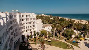 A multi-story hotel with balconies, a beach view, and palm trees. - Yadis Hammamet Club (Hammamet)