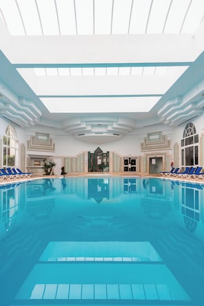 A large indoor swimming pool with blue water, surrounded by lounge chairs and a high ceiling with skylights. - Yadis Hammamet Club (Hammamet)