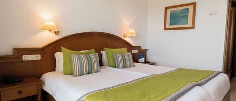 A hotel room with a large bed, two bedside lamps, a nightstand, and a framed picture on the wall.