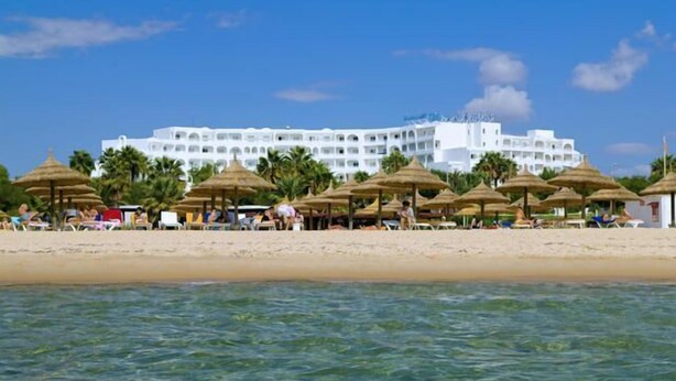 A beachfront hotel with multiple white buildings, palm trees, and beach umbrellas. - Yadis Hammamet Club (Hammamet)
