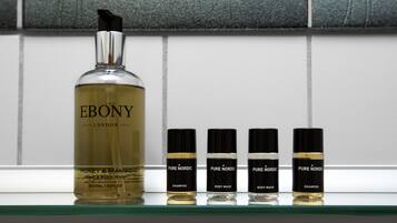 Una bottiglia di detergente corpo e mani Ebony London Honey & Mango e quattro flaconi di detergente corpo Pure Nordic su uno scaffale.