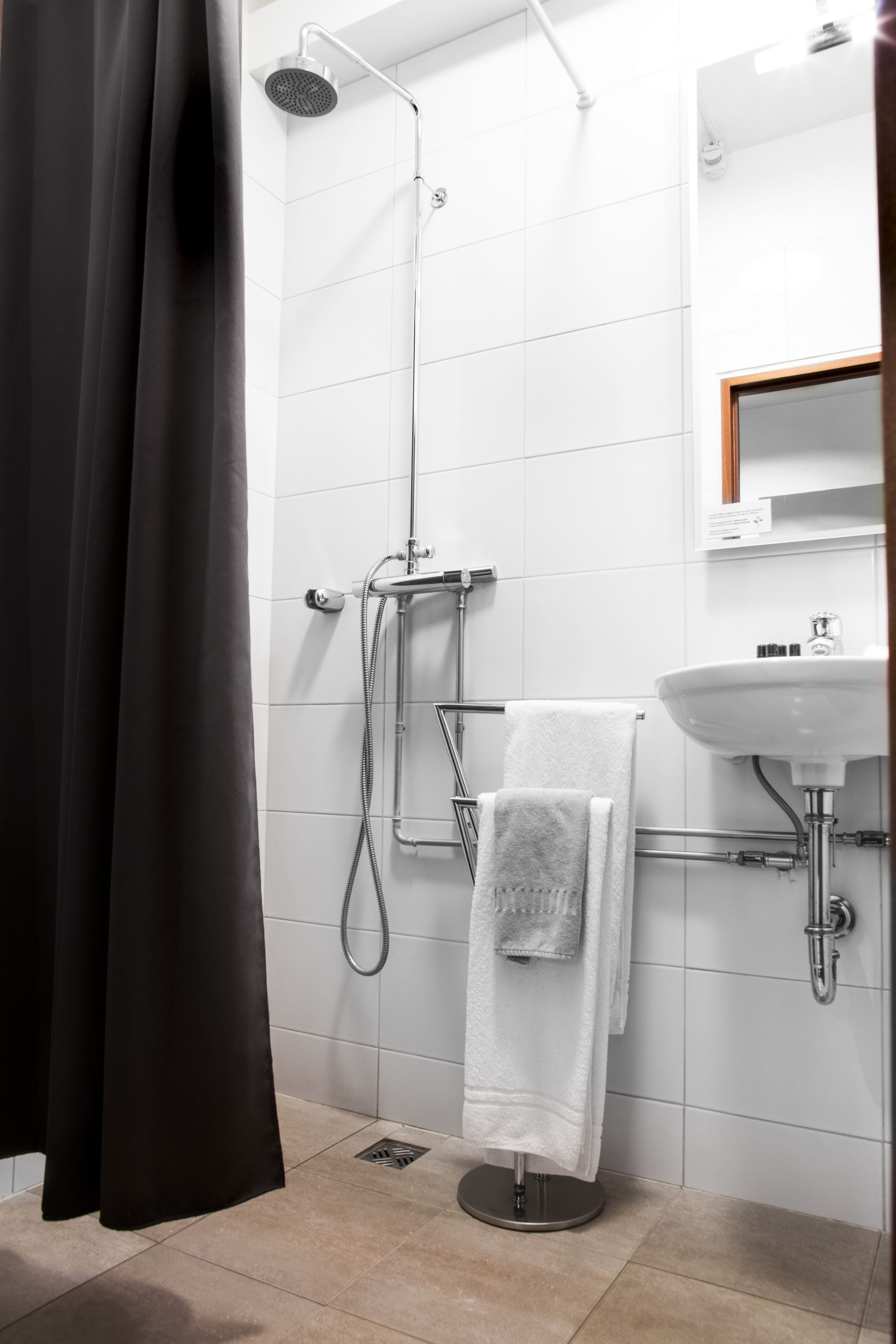 Une salle de bain moderne équipée d’une douche, d’un lavabo et d’un porte-serviettes.
