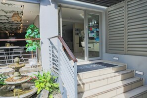 A modern outdoor entrance with a stone fountain, a staircase, and a glass door leading inside. - Atlantic Affair Boutique Hotel (Cape Town)