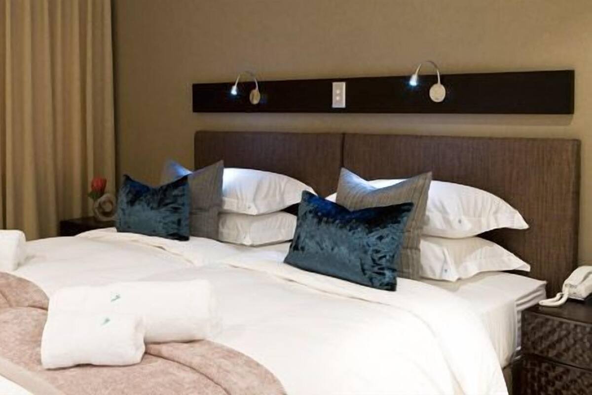 Une chambre d’hôtel avec un grand lit, plusieurs oreillers, une table de chevet avec une lampe et un téléphone.