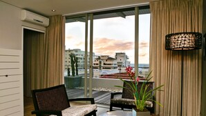 Een moderne hotelkamer met een groot raam, een bank, een salontafel en een vloerlamp.