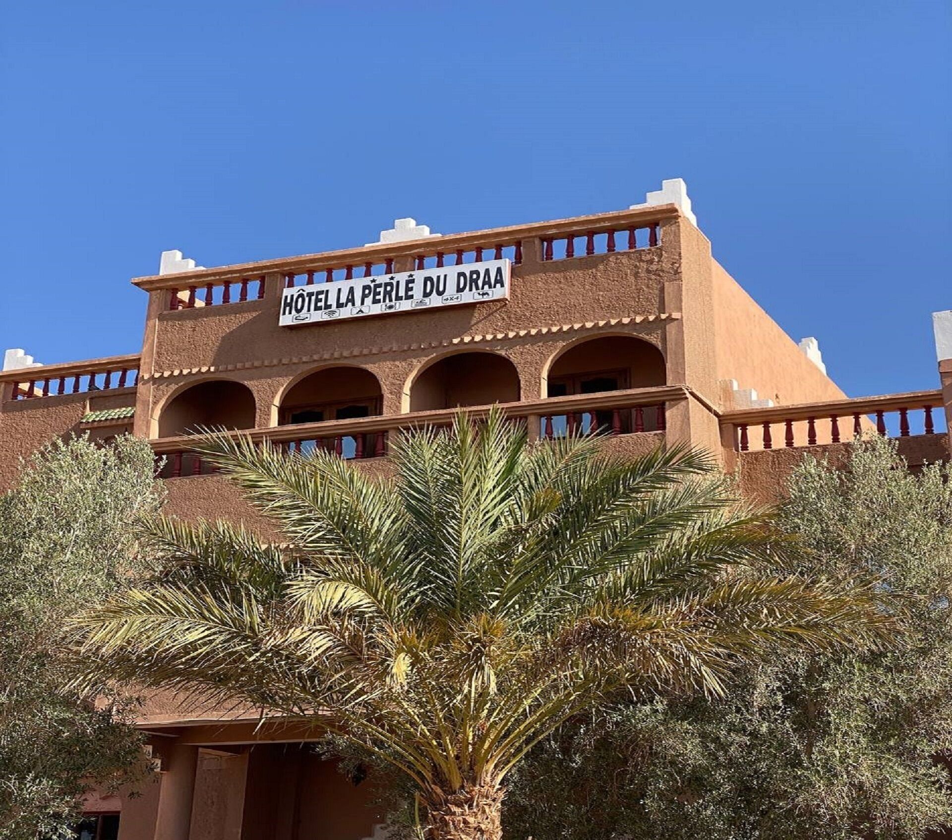 A building with a sign reading "HOTEL LA PERLE DU DRAA".