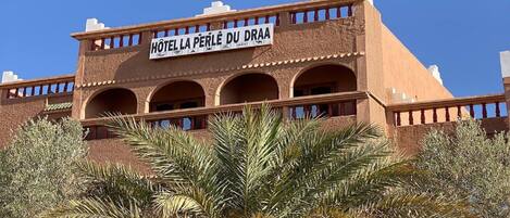 A building with a sign reading "HOTEL LA PERLE DU DRAA".