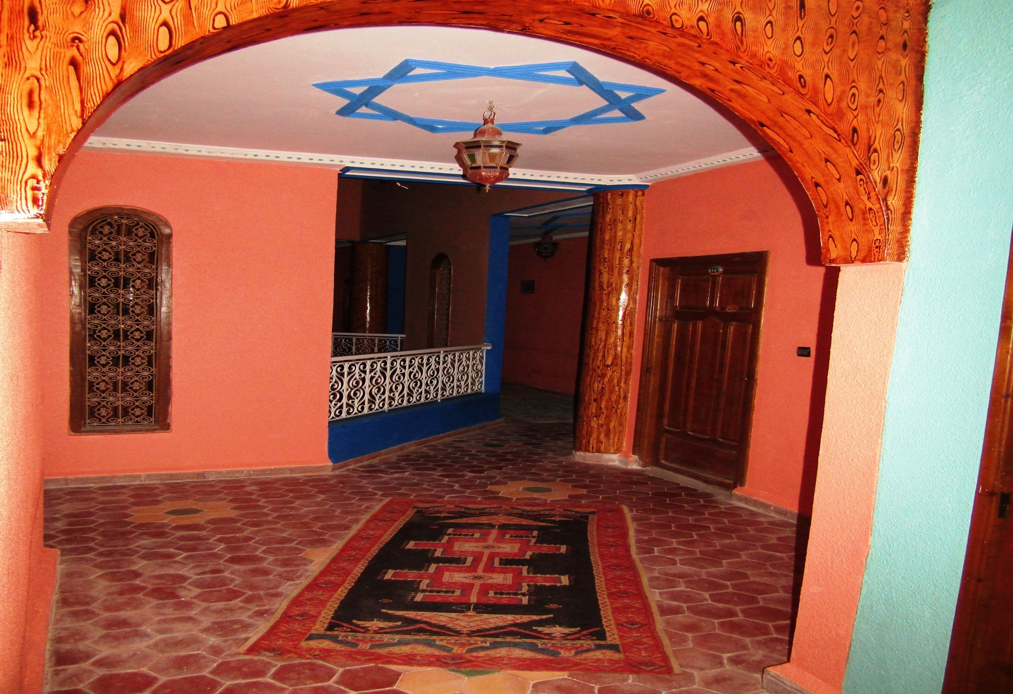 A hallway with a star-shaped ceiling design, a patterned rug, and a wooden door.