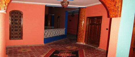A hallway with a star-shaped ceiling design, a patterned rug, and a wooden door.