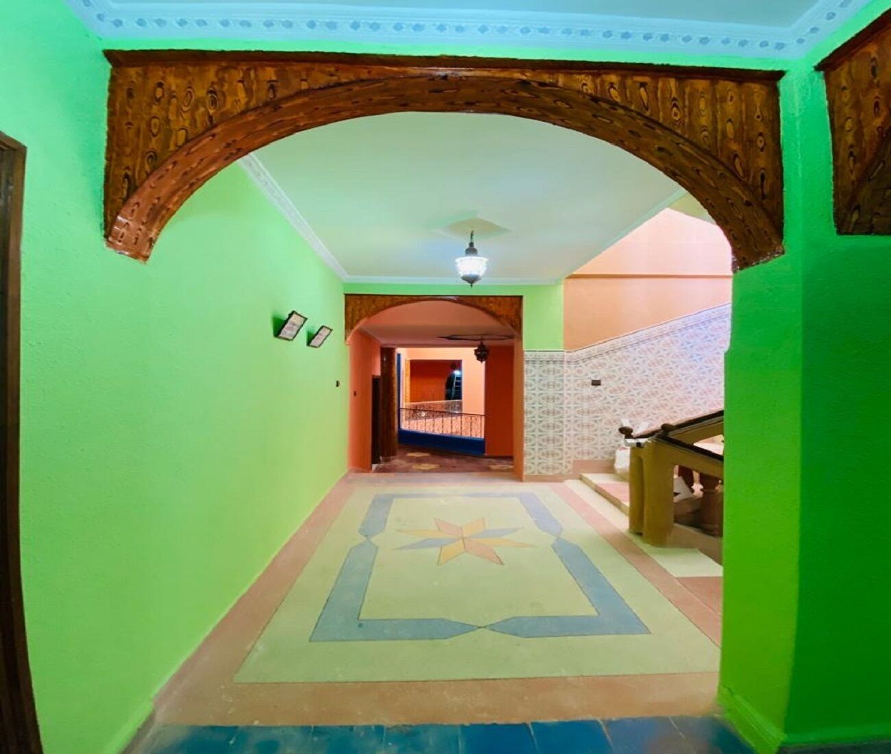 Un pasillo con un arco de madera, piso estampado y una escalera con barandilla.