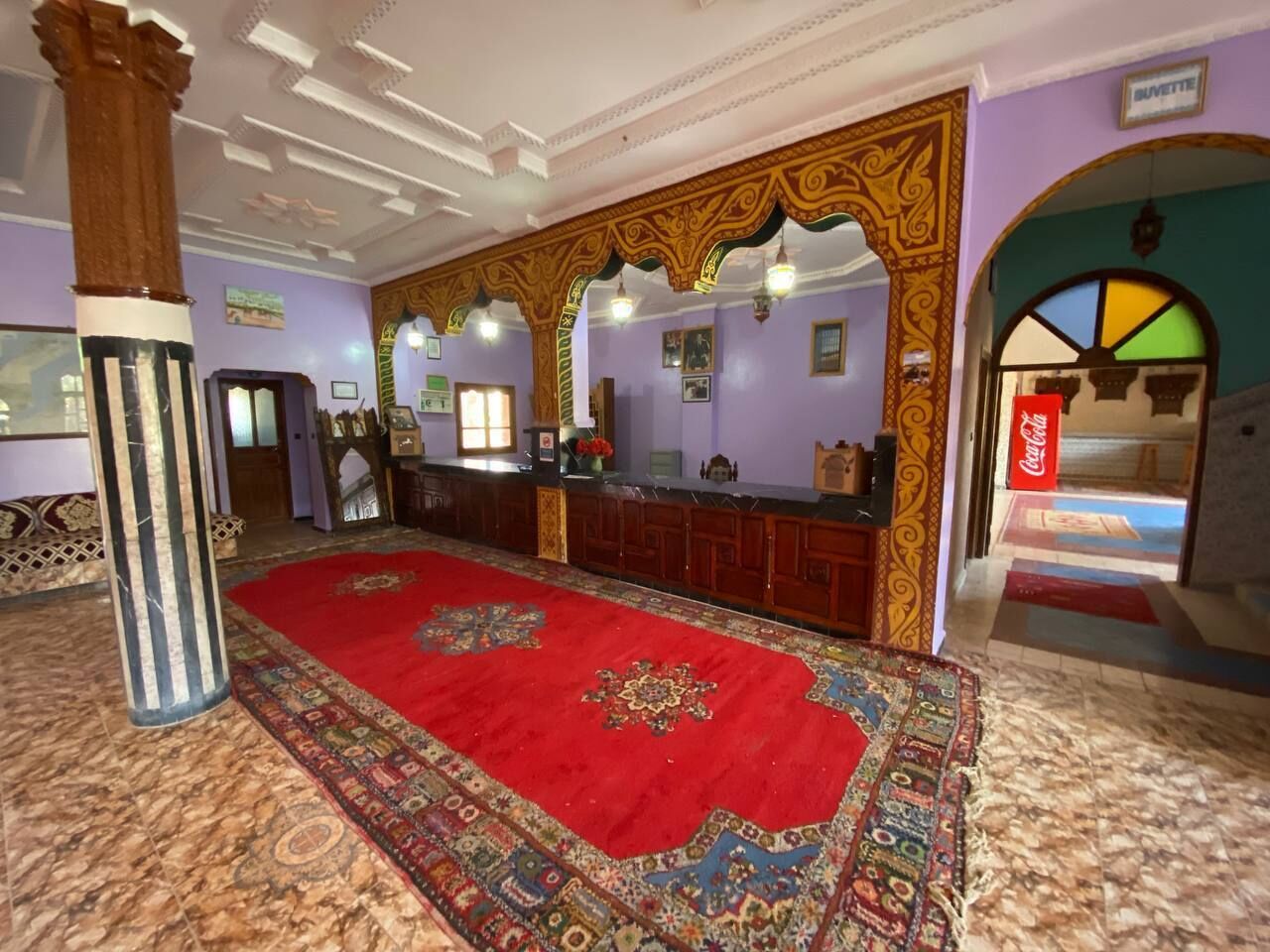 A lobby with a red carpet, wooden reception desk, and a Coca-Cola sign.