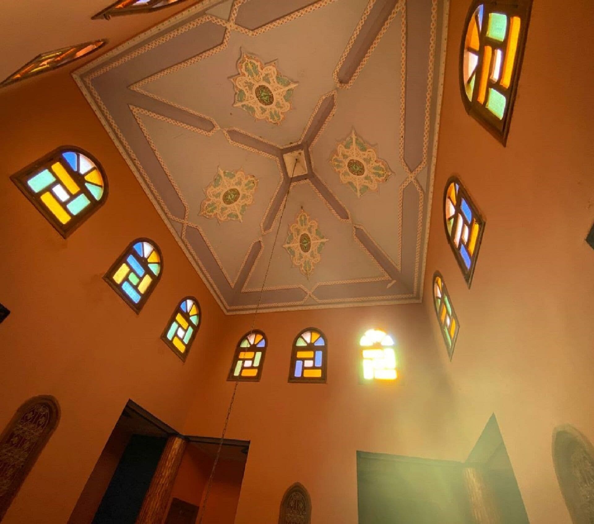 A room with a high ceiling featuring a geometric pattern and stained glass windows.