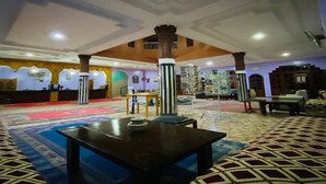 Eine großzügige Lobby mit hoher Decke, einer zentralen Säule und einem gemusterten Teppich.