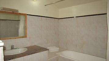Un baño con lavamanos, espejo y bañera.