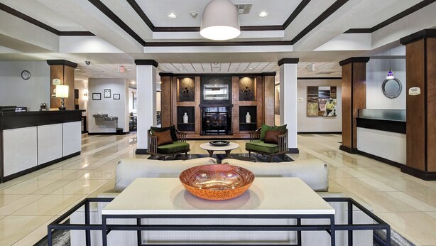 Um hall amplo com balcão de recepção, área de estar e uma grande tigela decorativa sobre uma mesa.