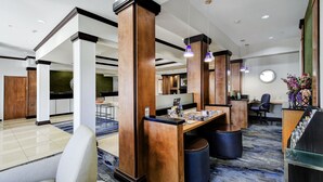 Um hall amplo com tetos altos, pilares de madeira e um balcão de recepção.