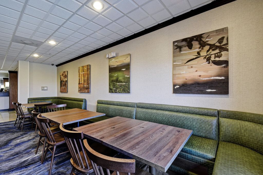 Un restaurante con una larga mesa de madera y asientos acolchados verdes.