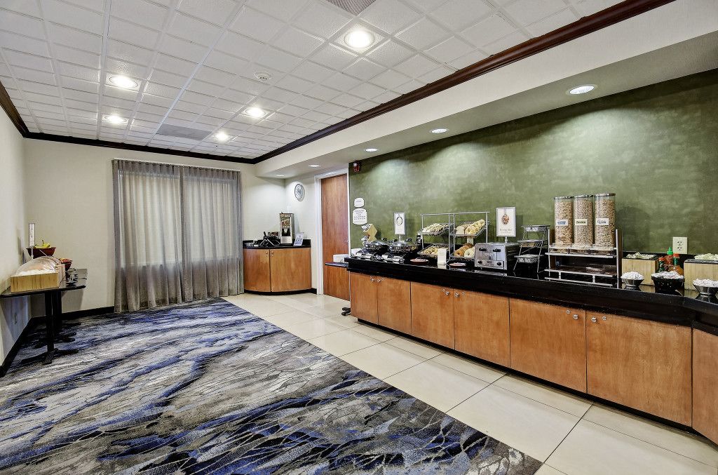 A hotel reception area with a counter, a clock, and a large window with curtains.