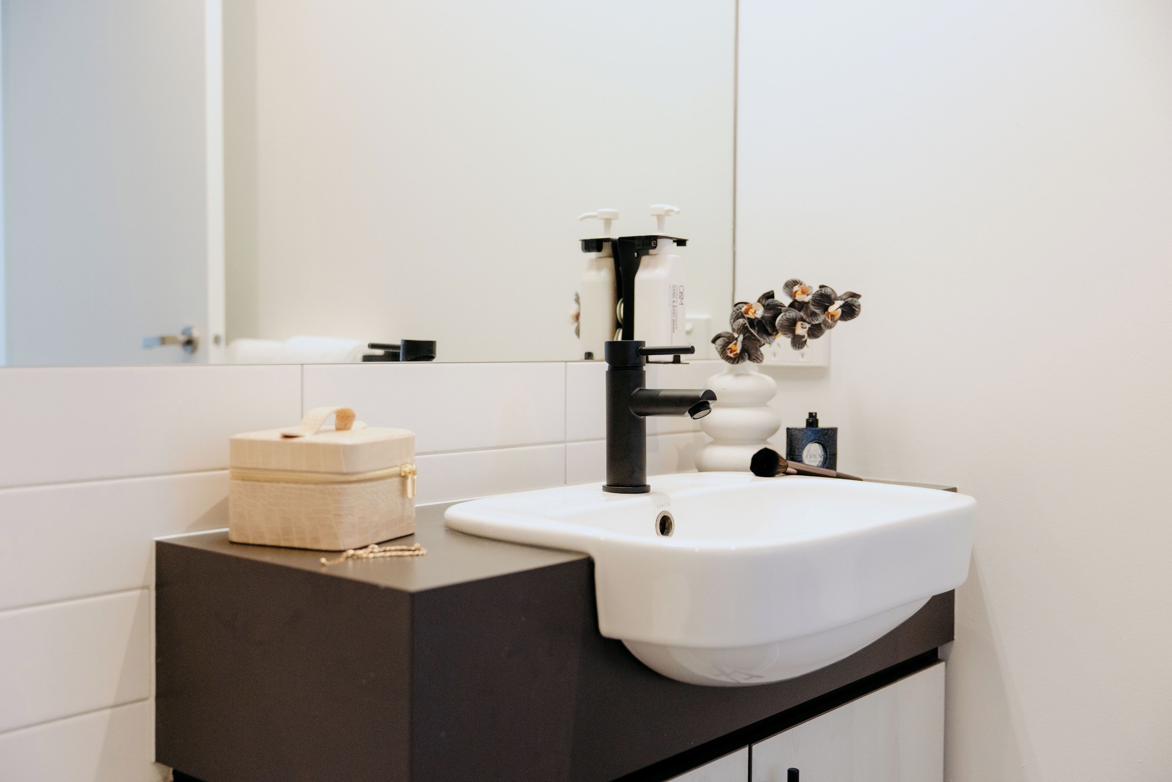 A bathroom with a white sink, black faucet, and a mirror above it.