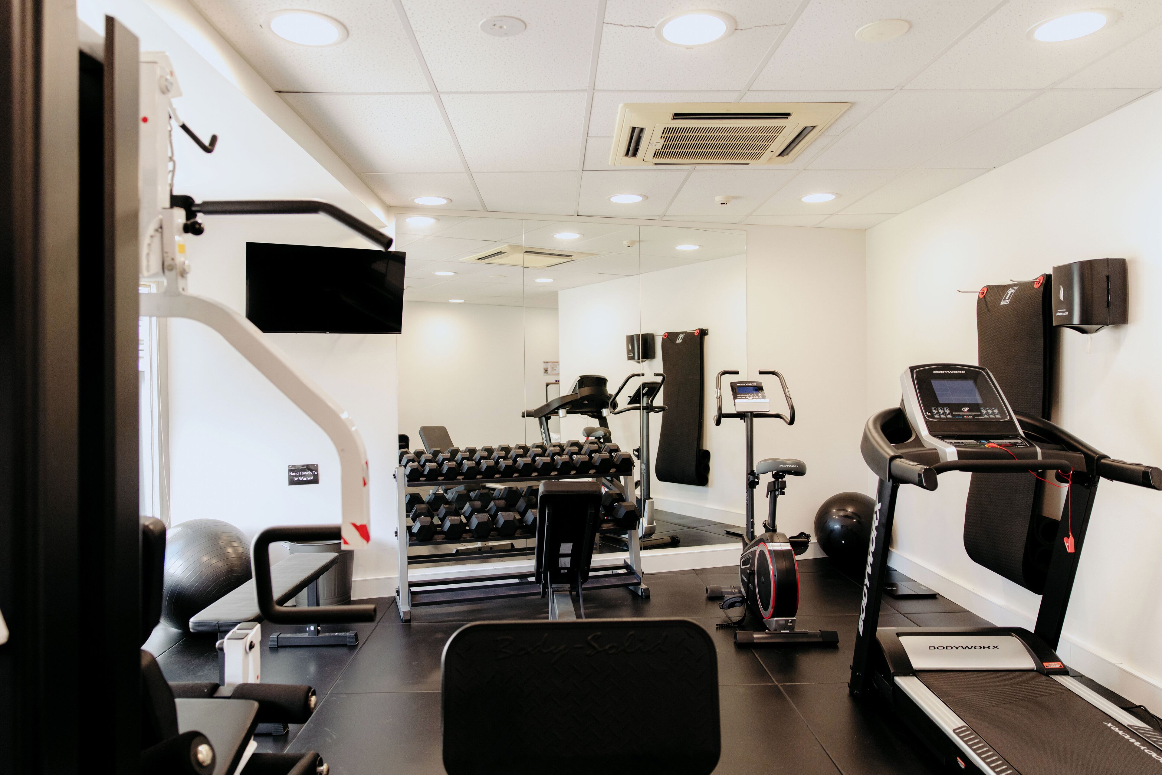 A gym with exercise equipment, a treadmill, and a mirror.