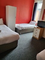 Hotelkamer met twee bedden, een kledingkast, een tv op een houten standaard en een raam met gordijnen.