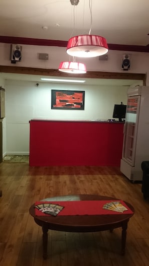 Ein Empfangsbereich mit einem roten Schreibtisch, einer hängenden roten Lampe, einem gerahmten Bild an der Wand und einem Verkaufsautomaten.