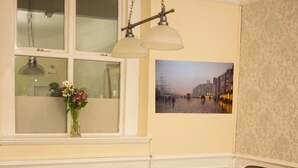 A living room with two brown leather sofas, a glass coffee table, a vase with flowers, and a wall-mounted picture of a street scene. - The Maple Hotel (Liverpool)
