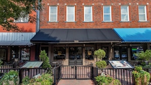 A brick building with a black awning and a sign that reads "Ricks." - The Grand Hotel (McKinney)