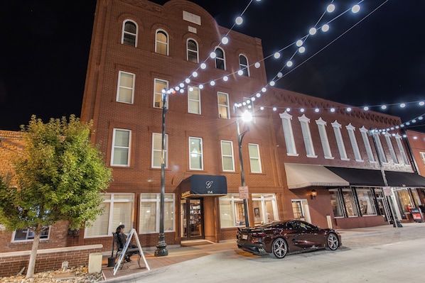A brick building with a storefront labeled "114" and a parked car.