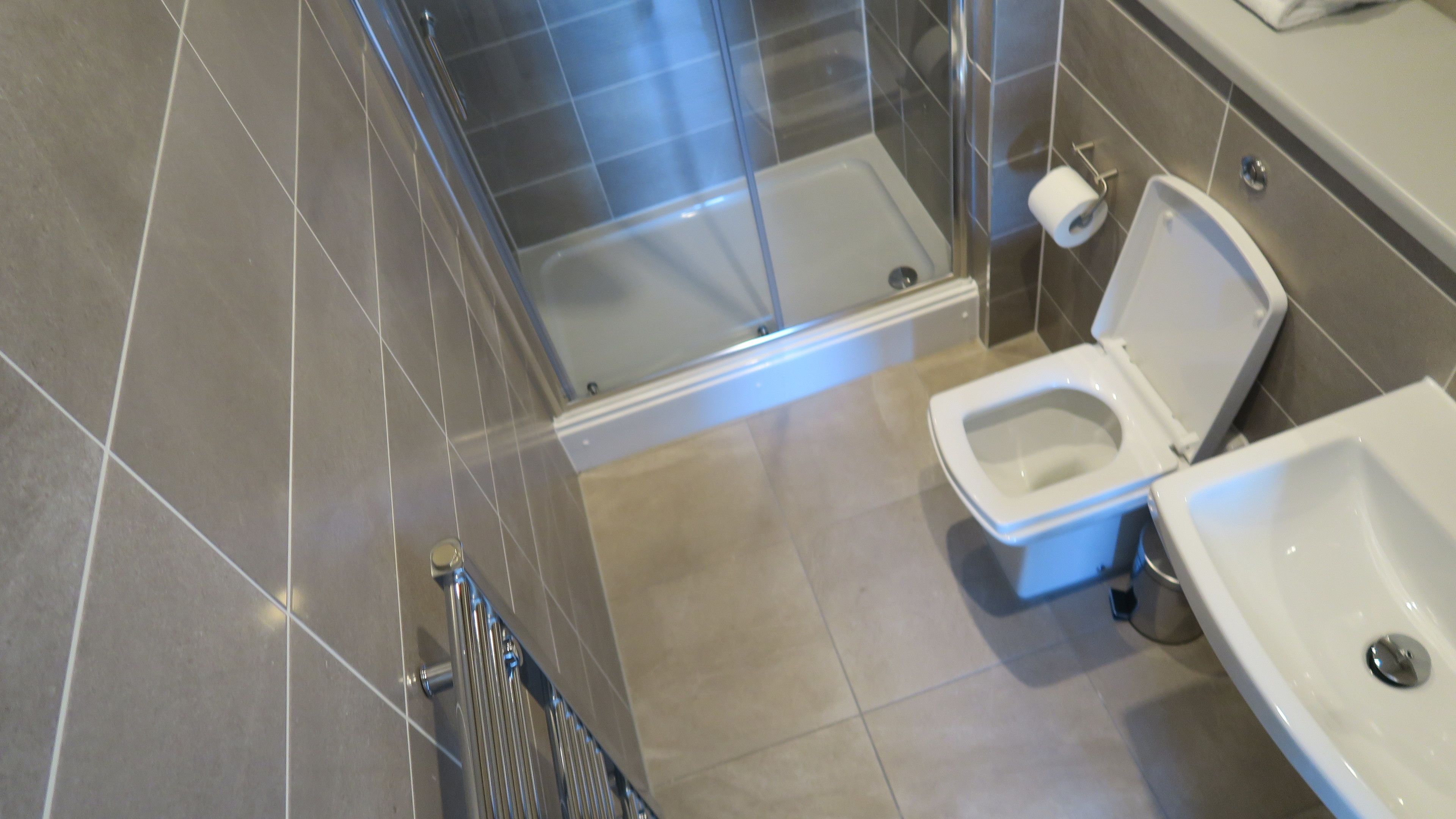 Ein modernes Badezimmer mit Glasdusche, Toilette und Waschbecken.