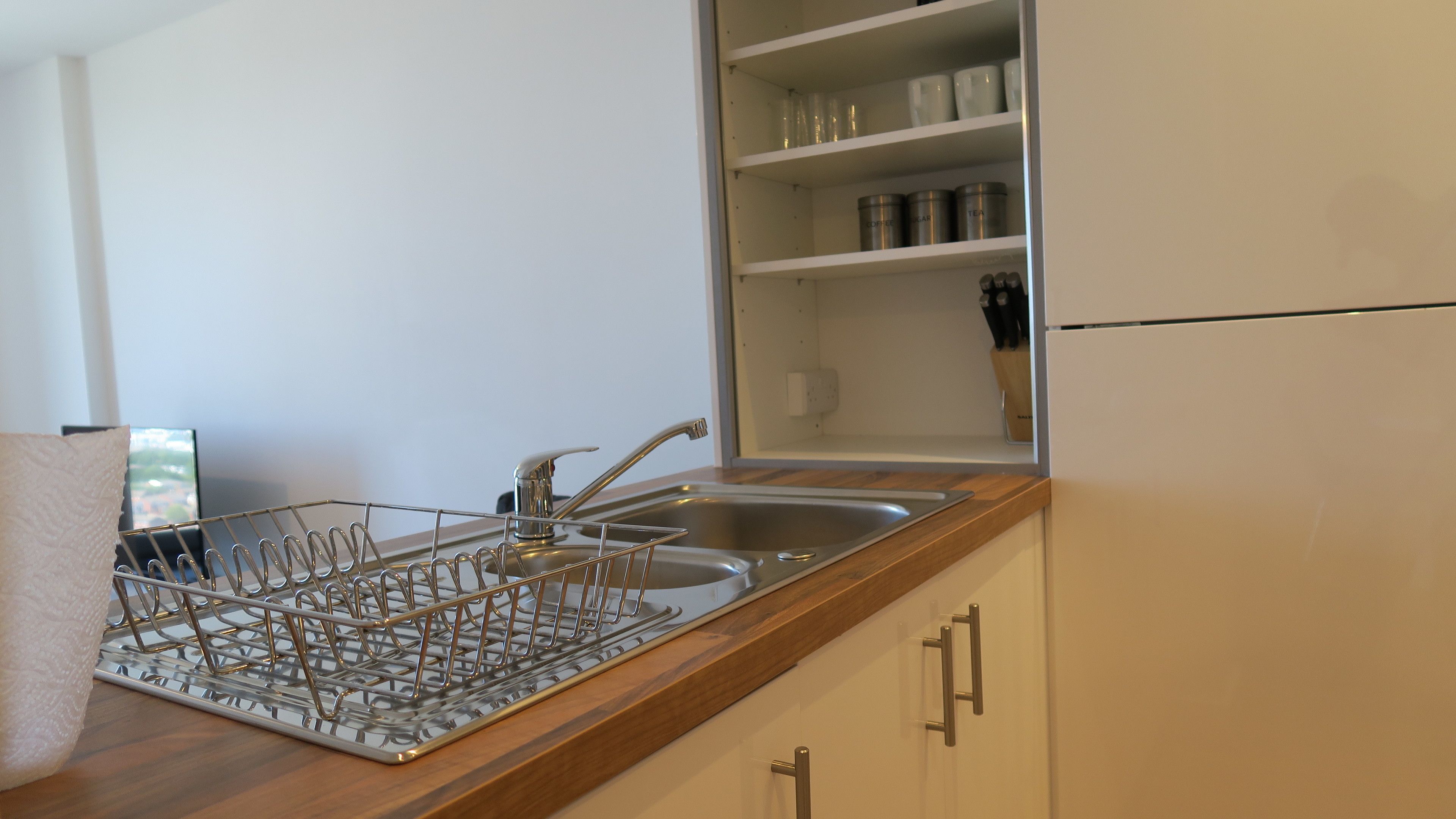 Una cucina con lavello in acciaio inossidabile, piano di lavoro in legno e mobili.