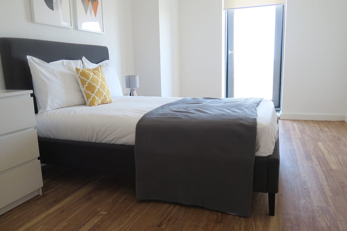 Um quarto moderno com uma cama, mesa de cabeceira e criado-mudo.