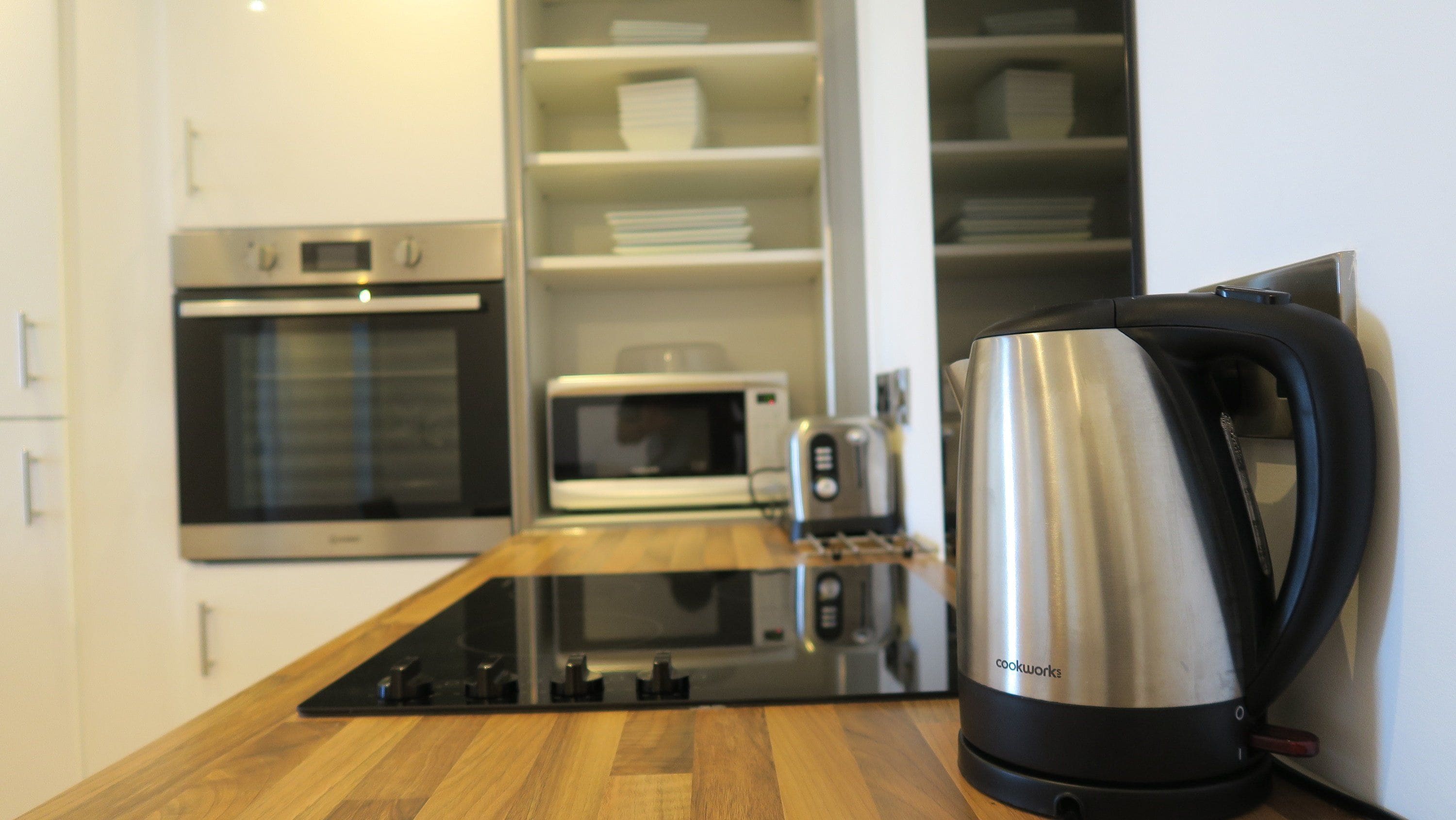A modern kitchen with a built-in stove, a microwave, and a kettle.