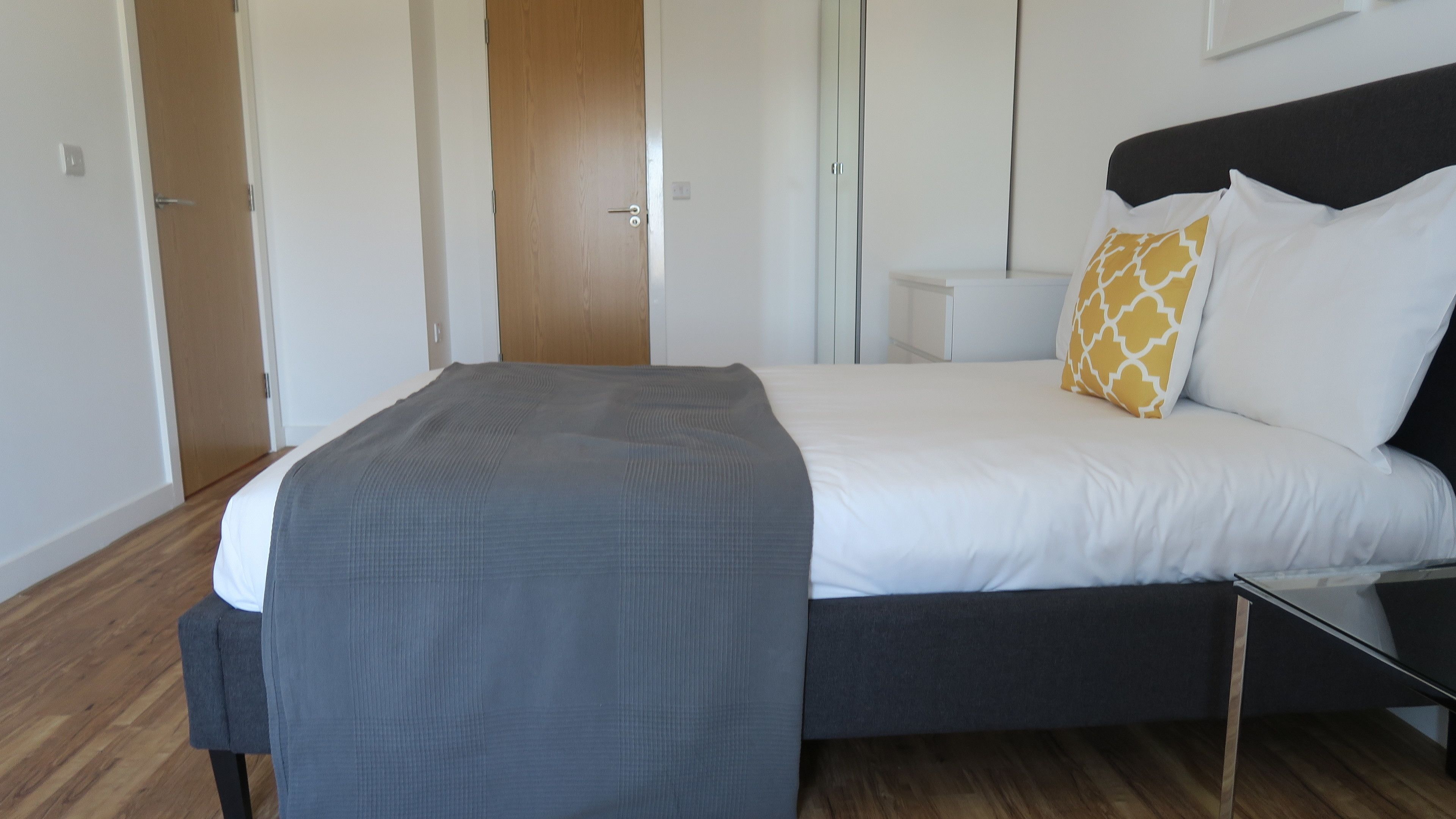 A modern bedroom with a bed, bedside tables, and a wardrobe.