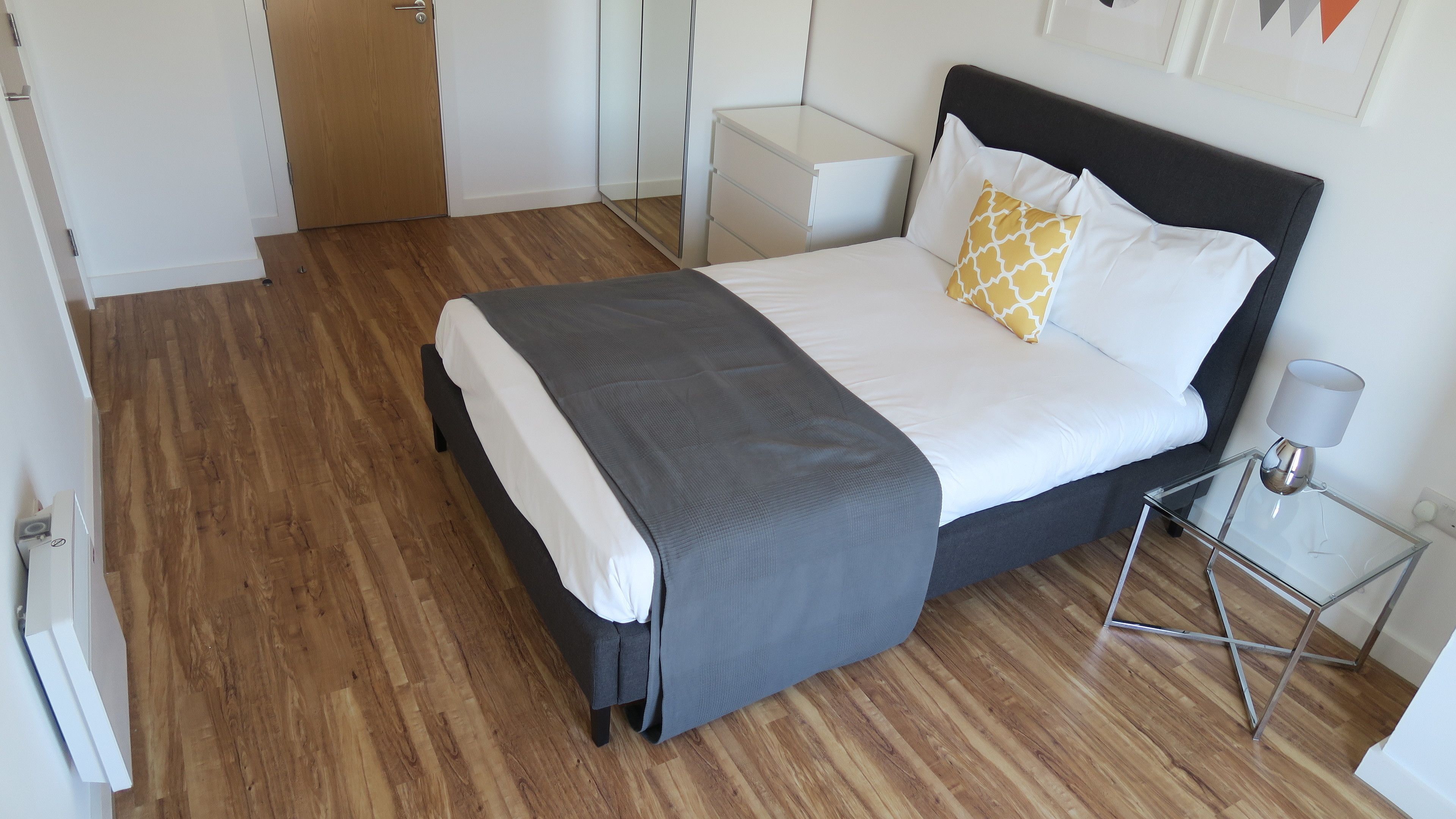 A neatly arranged bedroom with a bed, bedside table, and a lamp.