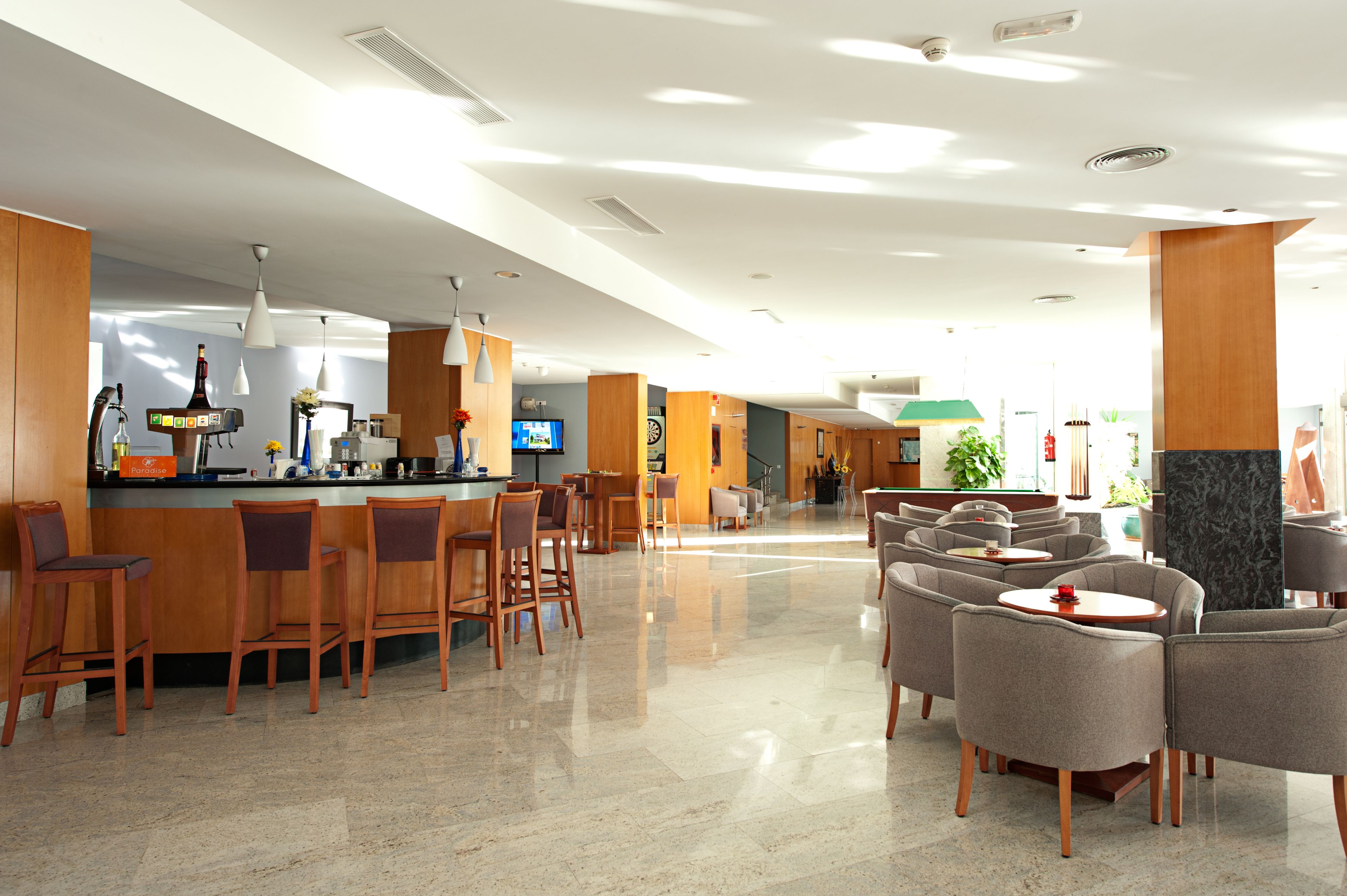 A modern hotel lobby with a bar area, seating arrangements, and a reception desk.