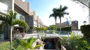 A modern hotel with a central courtyard, palm trees, and a water feature. - Hotel LIVVO Costa Taurito & Aquapark - All Inclusive (Mogan)