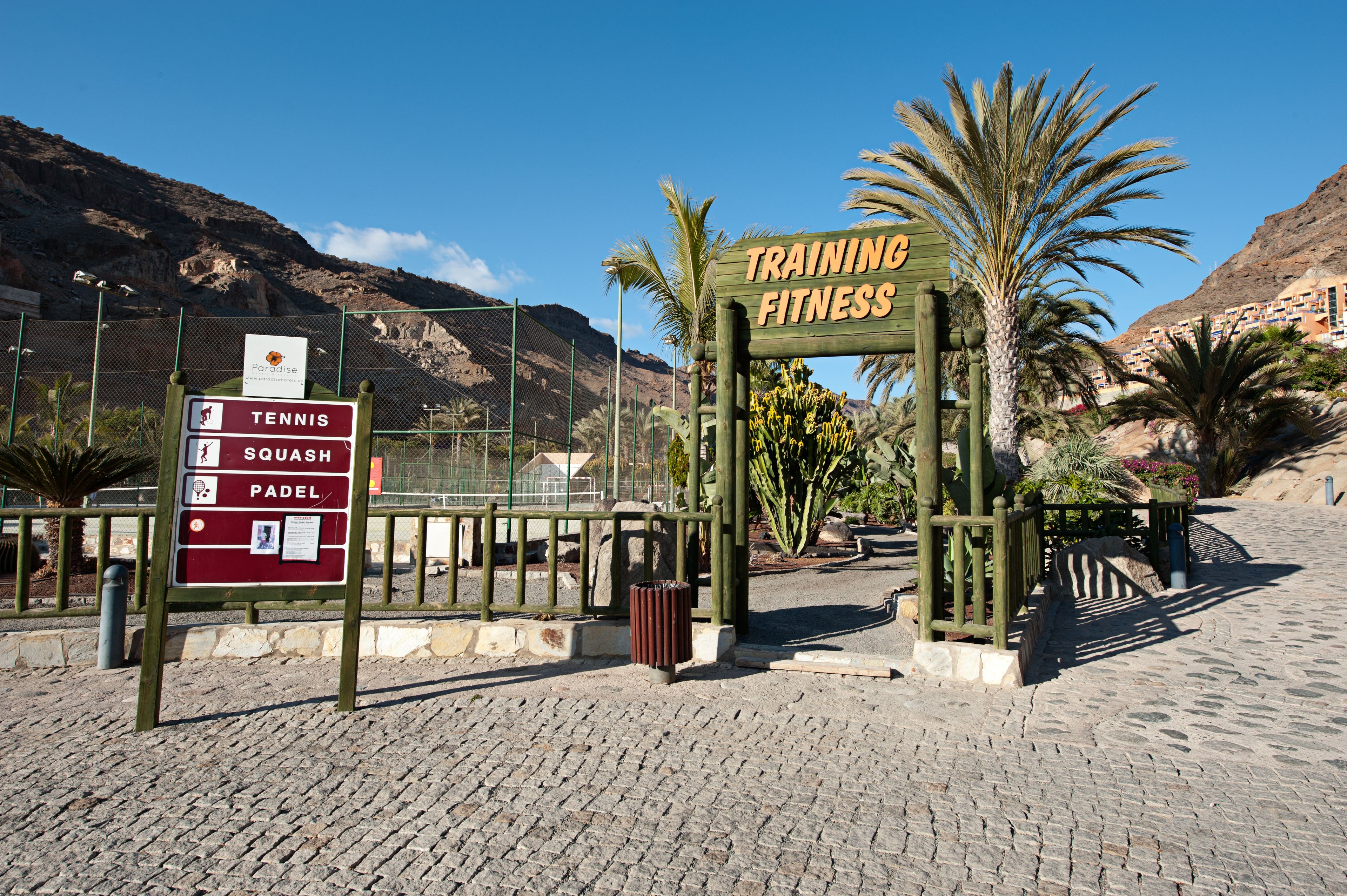 A sign for a training facility with a list of sports including tennis, squash, and padel.