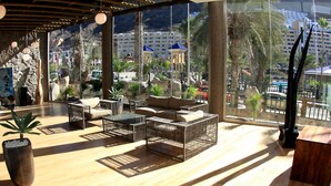 A spacious balcony with wooden flooring, wicker furniture, and potted plants. - Hotel LIVVO Costa Taurito & Aquapark - All Inclusive (Mogan)