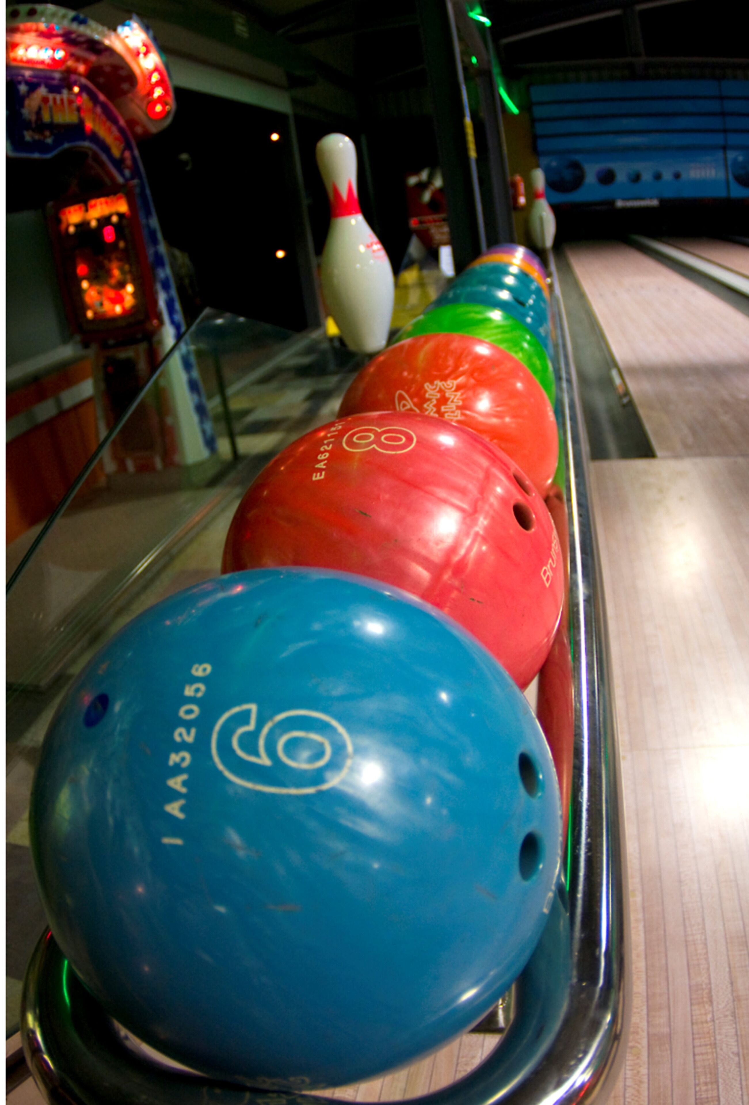 A bowling alley with a lane and several bowling balls lined up.