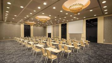 A conference room with rows of chairs, tables, and a projector screen.