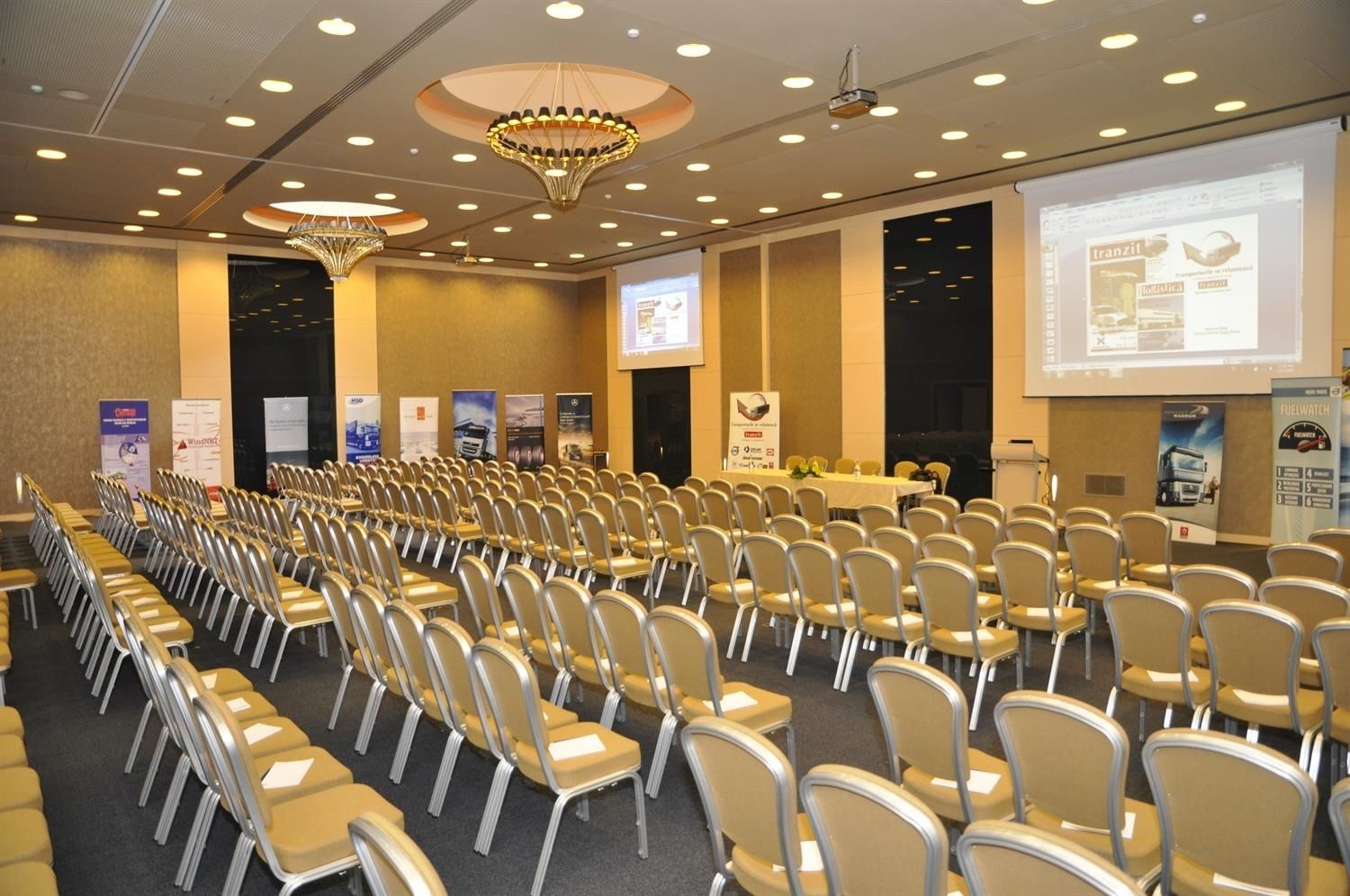 A conference room with rows of chairs, a projector screen, and banners on the walls.