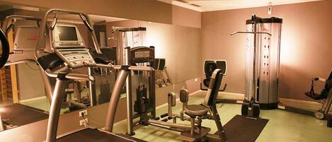 A gym with cardio equipment, weight machines, and a mirror.