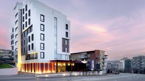A modern hotel with a prominent entrance, multiple floors, and a well-lit facade. - Golden Tulip Ana Dome (Cluj-Napoca)