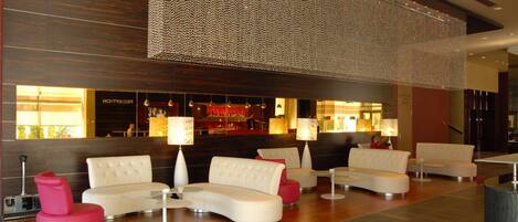 A modern lobby with a bar area, seating arrangements, and a decorative light installation.