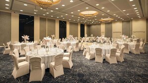 A banquet hall with round tables, chairs, and chandeliers. - Golden Tulip Ana Dome (Cluj-Napoca)
