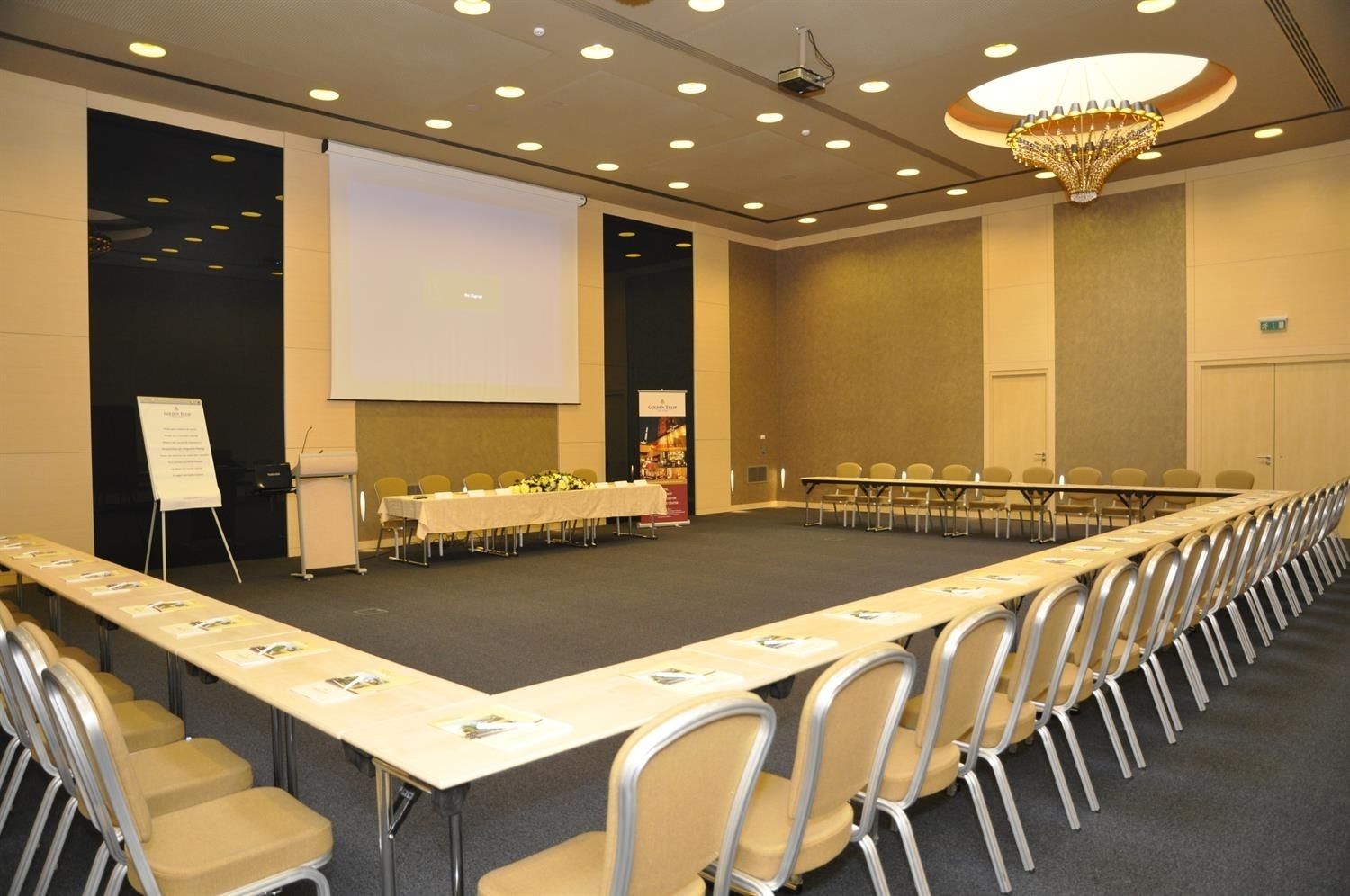 A conference room with a long table, chairs, a projector screen, and a whiteboard.