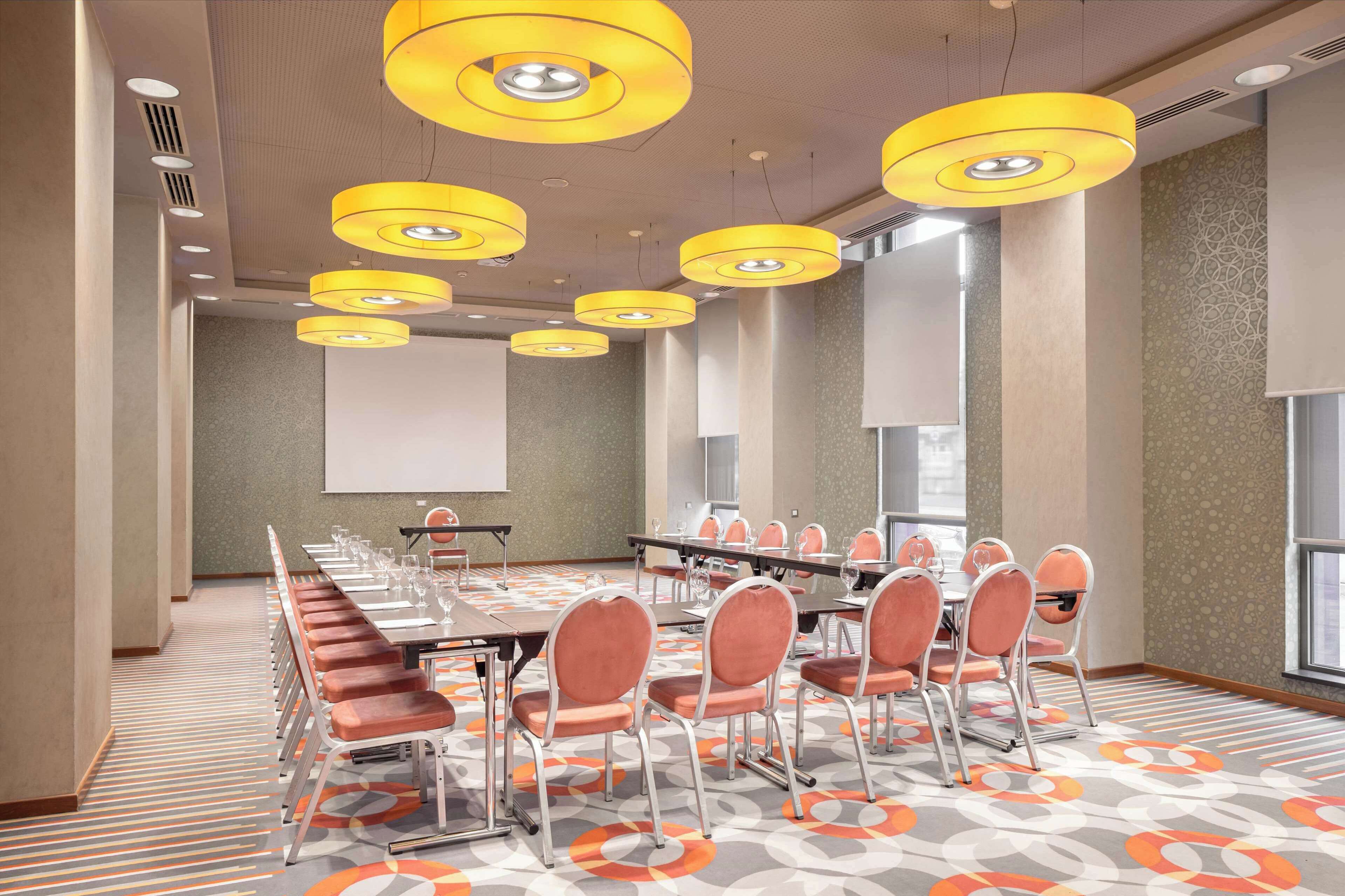 Une salle de conférence équipée d’une longue table, de chaises et d’un écran de projection.