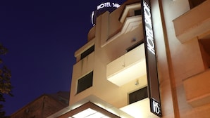 A hotel entrance with a staircase leading to the lobby, a sign indicating the hotel name, and a parked car in front. - Hotel Savoy (Timisoara)